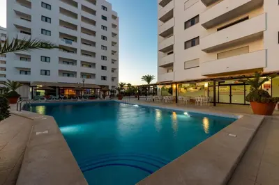 a swimming pool in front of two buildings at Albufeira Cozy Sea View with Balcony & Resort Access in Albufeira