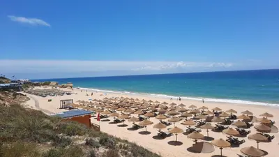 a beach with many umbrellas and chairs and the ocean at Villa Ocean Gale in Albufeira