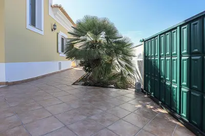a courtyard with a green fence and a palm tree at Villa Tio Pedro - Swimming Pool - For families- BY BEDZY in Albufeira