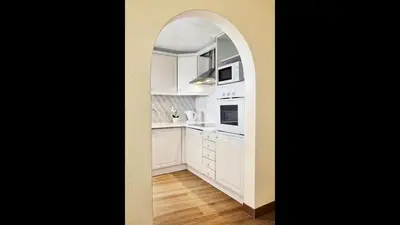 a kitchen with white cabinets and an archway at Amazing ApartHotel Apartments 2 Bedroom in Albufeira in Albufeira