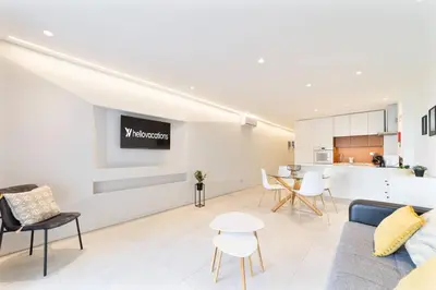 a living room with a couch and chairs and a kitchen at Saro Apartment by HelloVacations in Albufeira