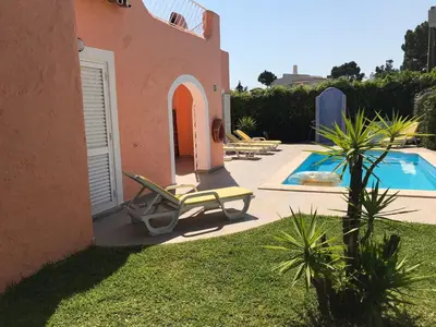 a resort with a pool and chairs and a house at Toiago in Vilamoura