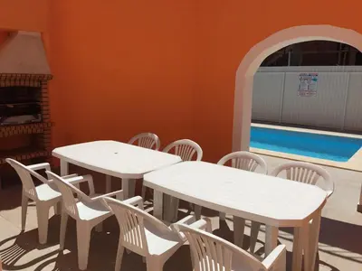 two white tables and chairs in a room with a pool at Toiago in Vilamoura