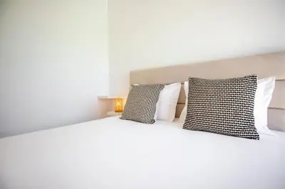a white bed with two black and white pillows at Beautiful Villa with a Pool in Albufeira