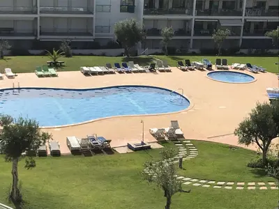 a dining room with a white table and chairs at Penthouse, sea view, tennis, swimming pools, 3' foot golf in Olhos de Água
