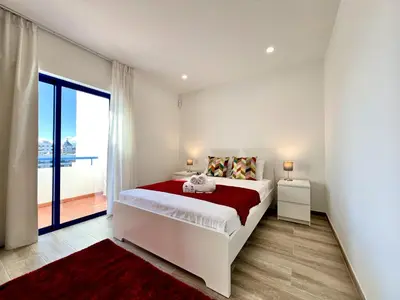 a white bedroom with a bed and a large window at Vilamoura Design 2 by Homing in Vilamoura