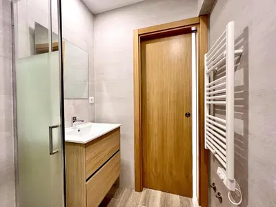 a bathroom with a sink and a wooden door at Vilamoura Design 2 by Homing in Vilamoura