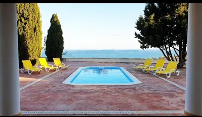 a swimming pool with yellow chairs and a group at Casa da Vigia - waking up in front of the sea in Albufeira