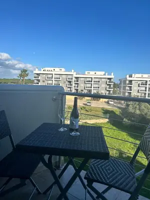 a table with a bottle and two glasses on a balcony at Fernandes Holidays in Quarteira