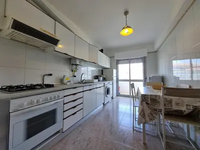 a kitchen with white appliances and a table and a dining room at TAC - Bright Coast Quarteira in Quarteira