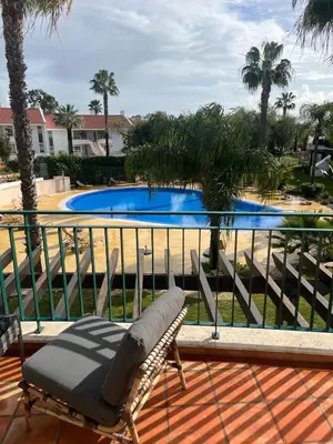 a chair on a balcony with a swimming pool at SomeSunnyDay Vila Sol Village in Quarteira
