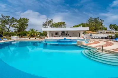 a large pool with blue water in front of a building at BmyGuest - Quinta do Lago Cosy Apartment in Quinta do Lago