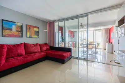 a living room with a red couch and a dining room at Beachfront apartment Praia dos Aveiros in Albufeira