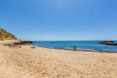 two people standing on a sandy beach near the ocean at Beachfront apartment Praia dos Aveiros in Albufeira