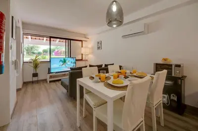 a dining room and living room with a white table and chairs at Apartamento Condomínio Montechoro by CM Properties in Albufeira