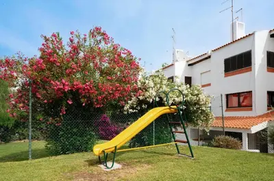 a yellow slide in a yard next to a building at Apartamento Condomínio Montechoro by CM Properties in Albufeira