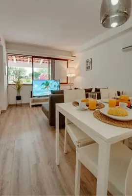 a living room with a dining room table and a tv at Apartamento Condomínio Montechoro by CM Properties in Albufeira