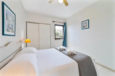 a white bedroom with two beds and a window at Passport Beach - 201 by HelloVacations in Albufeira