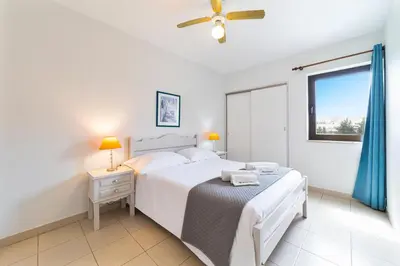 a white bedroom with a bed and a window at Passport Beach - 201 by HelloVacations in Albufeira