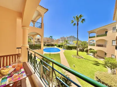 a balcony with a table and a view of a yard at Vilamoura Beach Village 1 With Pool by Homing in Vilamoura