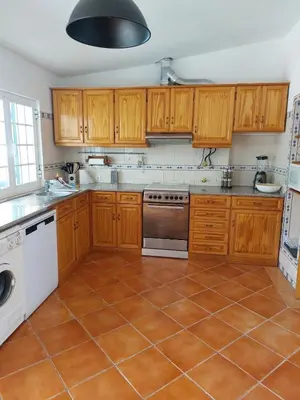 a kitchen with wooden cabinets and a tile floor at Quinta da Calma with pool and BBQ in Boliqueime