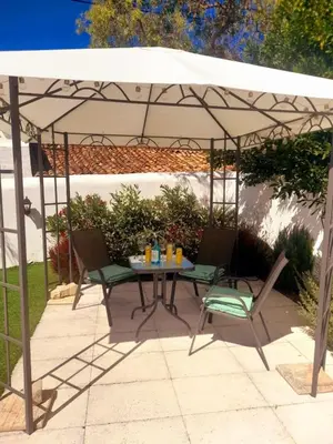 a patio with a table and chairs under a tent at Quinta da Calma with pool and BBQ in Boliqueime