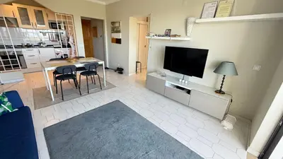 a living room with a television and a table with chairs at Cozy Sea View in Albufeira
