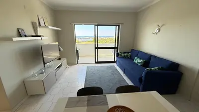 a living room with a blue couch and a table at Cozy Sea View in Albufeira