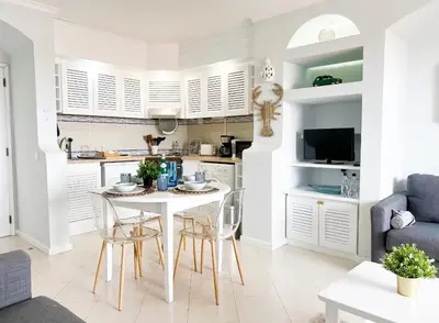 a white kitchen with a white table and chairs at Sea View Apartment Albufeira in Albufeira