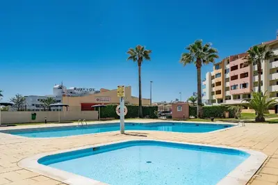 a large swimming pool with palm trees and buildings at Sea View Apartment Albufeira in Albufeira