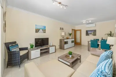 a living room with a couch and a tv at Pool with Beach 10' Away - Comfort and Tranquility in Quarteira