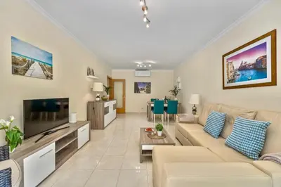 a living room with a couch and a tv at Pool with Beach 10' Away - Comfort and Tranquility in Quarteira