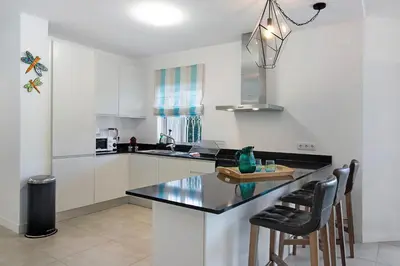 a kitchen with white cabinets and a black counter top at Beautiful 2 Bedroom Self Catering Apartment with Private Pool and Garden in the Encosta do Lago Resort in Quinta do Lago in Quinta do Lago