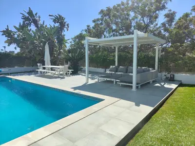 a pergola next to a swimming pool with a patio at Vila orada lola in Albufeira