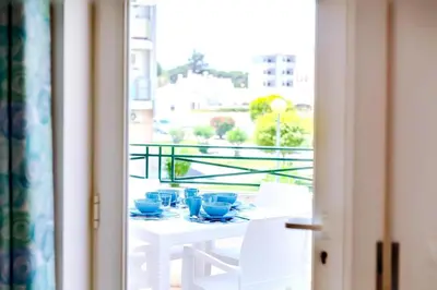 a table with blue cups and plates on a balcony at Falesia beach Pool quiet side by Enjoyyourstay in Albufeira