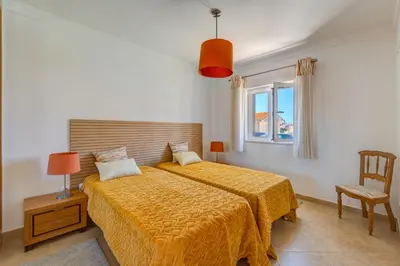 a bedroom with a bed with a yellow comforter and a window at Villa Ancora - Nex to the Beach - Parking - Swimming Pool - BY BEDZY in Albufeira
