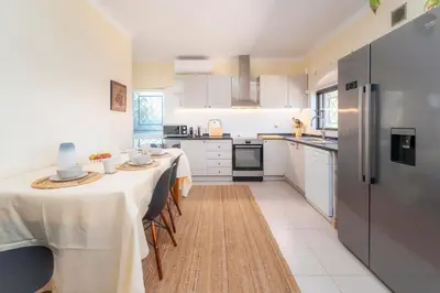 a kitchen with two tables and a refrigerator at Villa 4 Quartos, Piscina, BBQ Snooker, Prestige For Home in Quarteira