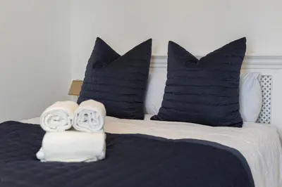 a bed with black and white pillows and two towels at Vilamoura Retreat - Sunset View by HD in Vilamoura