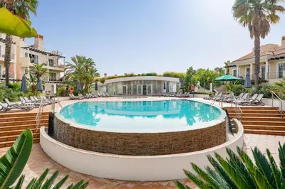 a pool at a resort with chairs and a building at Palmyra Apartments in Vilamoura in Vilamoura