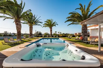 a pool with a hot tub next to palm trees at Villa Las Rosas in Albufeira