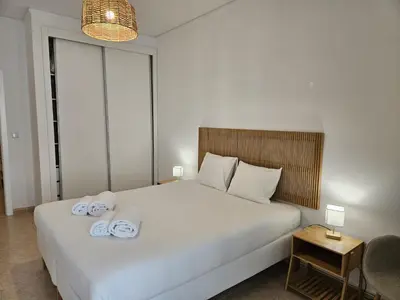 a bedroom with a large white bed with towels on it at Apartamento moderno na praia com varanda grande in Quarteira