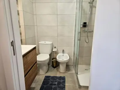a small bathroom with a toilet and a shower at Apartamento moderno na praia com varanda grande in Quarteira