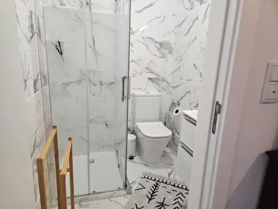 a white bathroom with a shower and a toilet at Apartamento moderno na praia com varanda grande in Quarteira