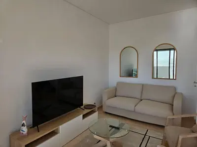 a living room with a couch and a flat screen tv at Apartamento moderno na praia com varanda grande in Quarteira