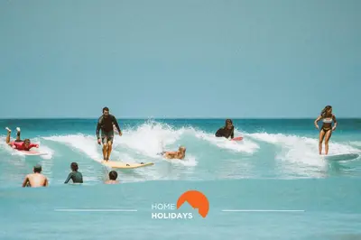 a group of people riding a wave on surfboards in the ocean at #275 Only Families - A Flor by Home Holidays in Albufeira