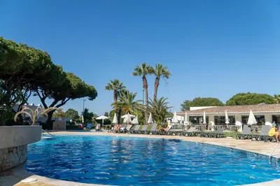 a swimming pool at a resort with palm trees at Luxury Beach House Apartment - Golf & Tennis Court & Pool View in Albufeira