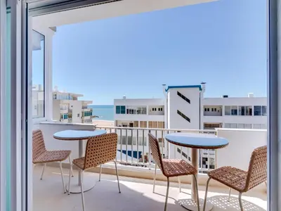 a balcony with tables and chairs and a view of the ocean at Art and Sea 2 bedroom apartment in Quarteira