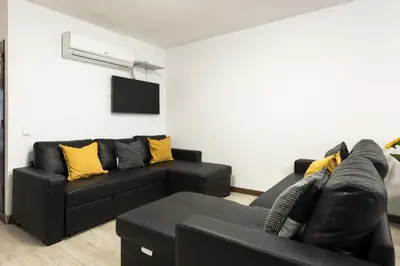a living room with a black couch and yellow pillows at Fonte Moura - With pool by HD in Vilamoura