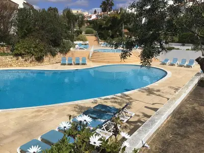 a large swimming pool with lounge chairs in a resort at 2 Bedroom Townhouse, Vale de Parra in Guia