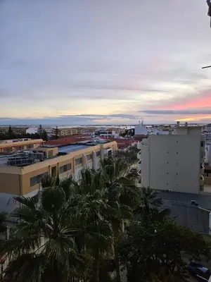 a sunset over a city with palm trees and buildings at Apartamento moderno com vista para o mar em Faro in Faro